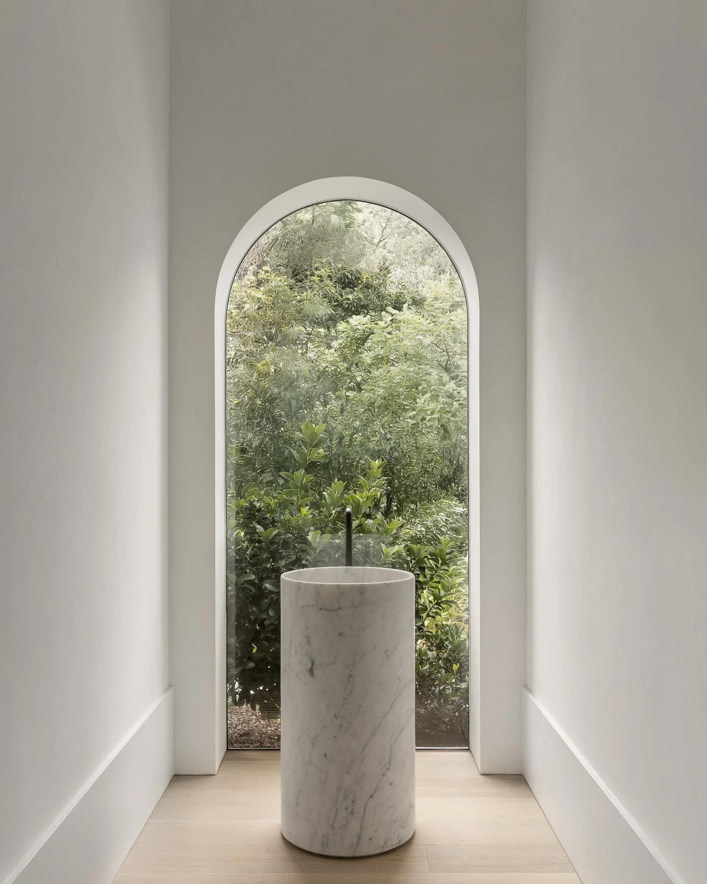 Framing nature in soft elegance. Our hand-finished Venetian plaster walls draw the eye toward a lush garden vista, creating a serene dialogue between craftsmanship and landscape. The subtle texture and natural light work in harmony, enhancing the roo
