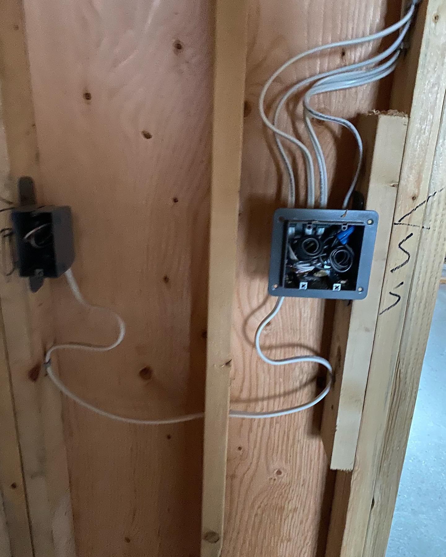 Electrical box with white wires inside and white wires running to switches on a wooden board.