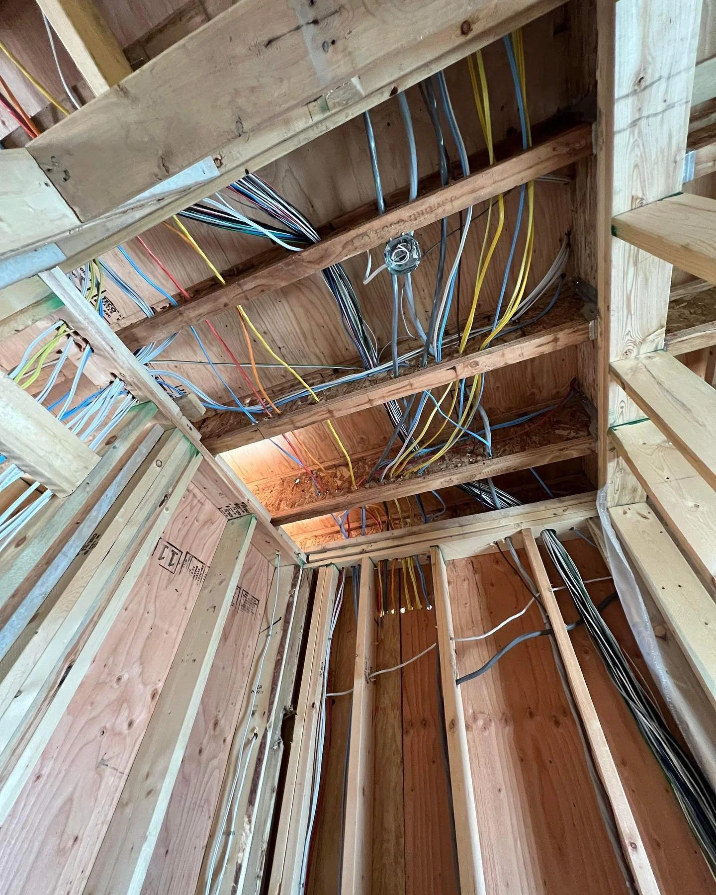 Inside view of a building under construction showing a wooden framework with electrical and communication wiring installed.