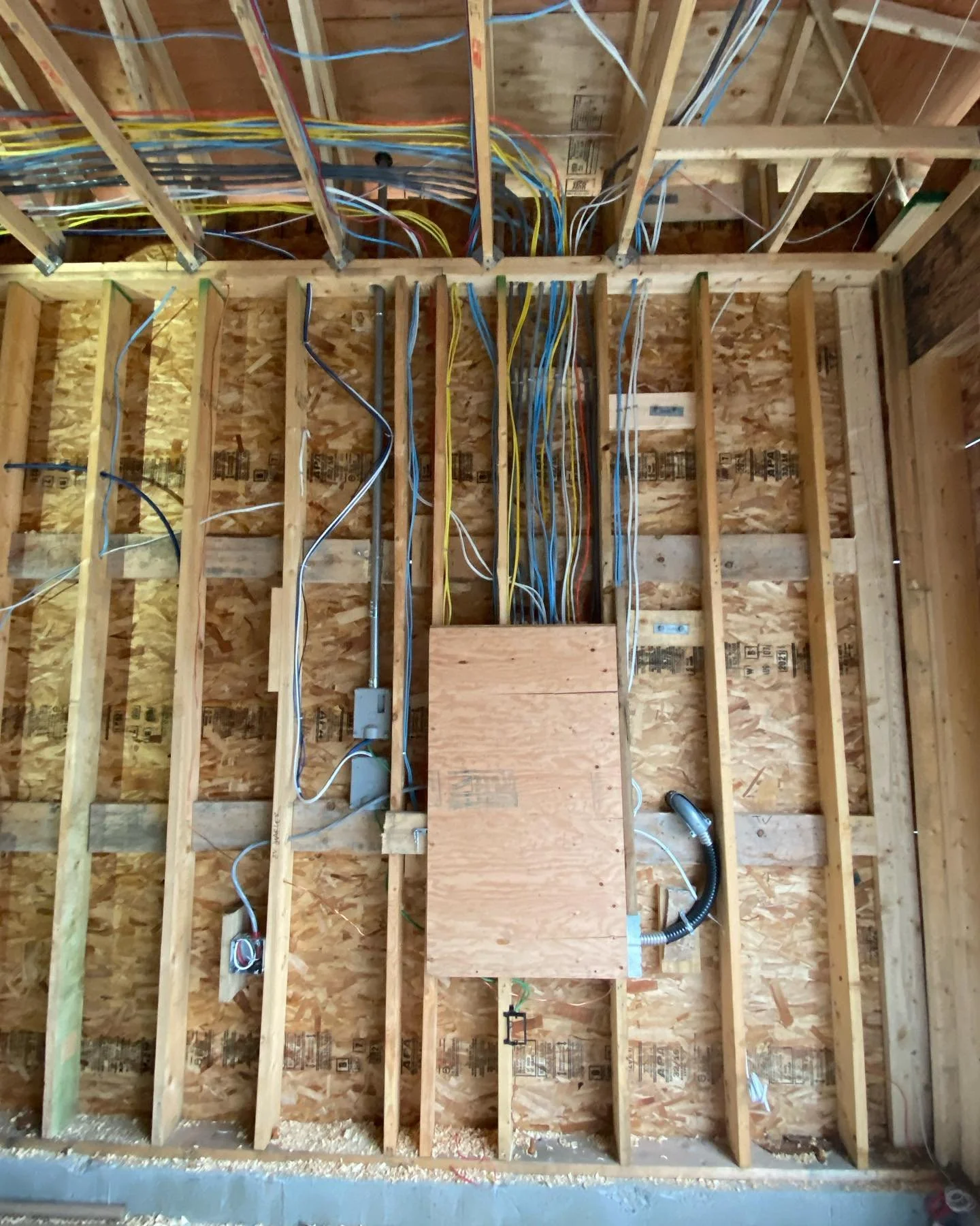 The interior of a construction site showing wooden framing, electrical wiring, and some electrical boxes on the wall.