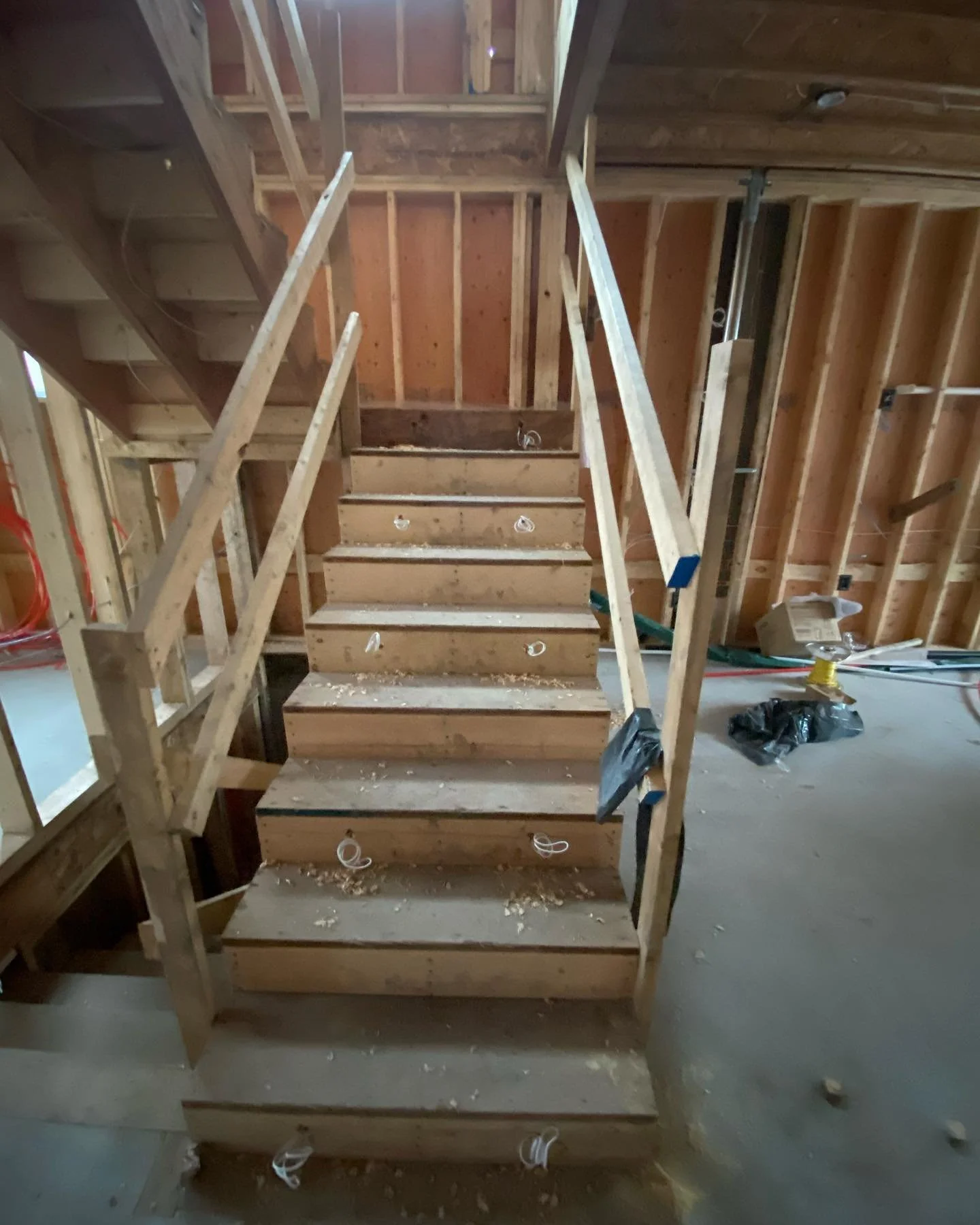 Construction site with wooden staircase framework and exposed wall studs.