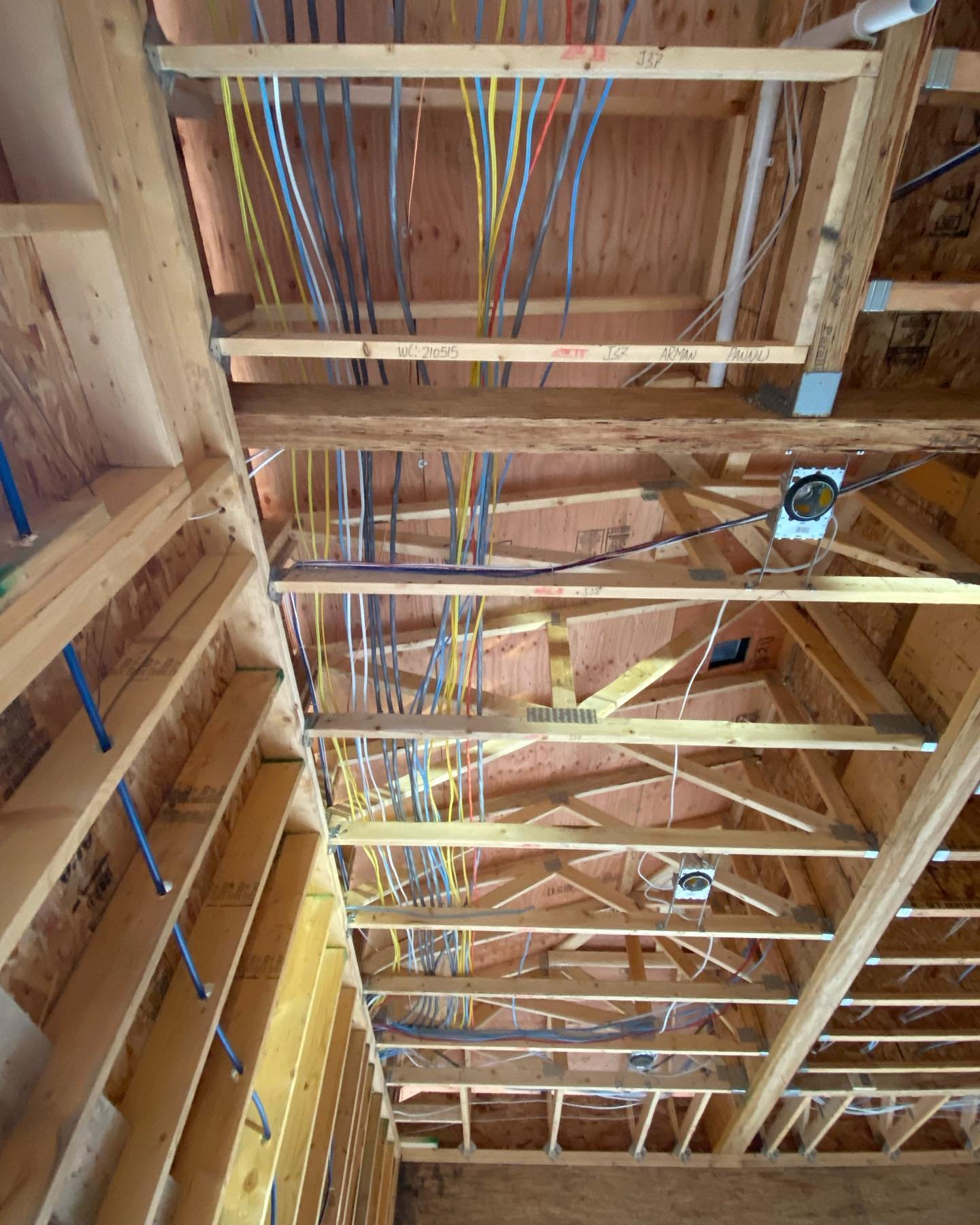 Construction framing of a ceiling with wooden beams and electrical wiring installed.