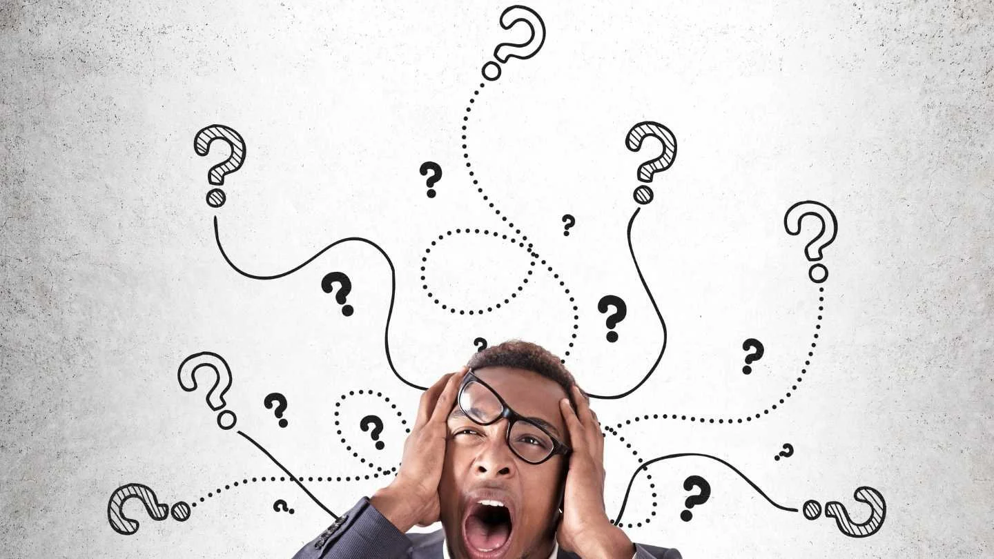 man with galsses and an open mouth with question marks above his head