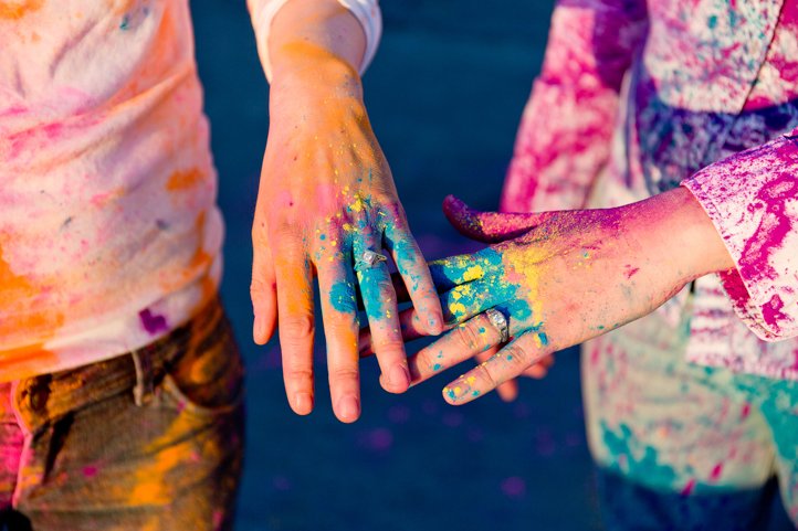 Close up of Alice &amp; Catie's rings and hands covered in colorful Holi powder