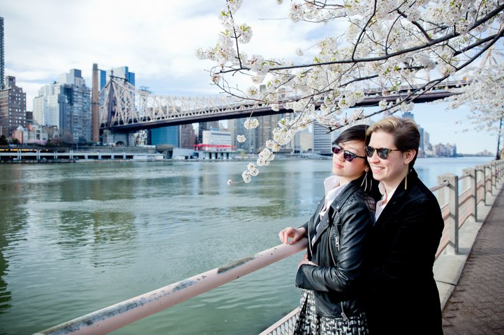Catie &amp; Alice embrace along the river with manhattan in the background