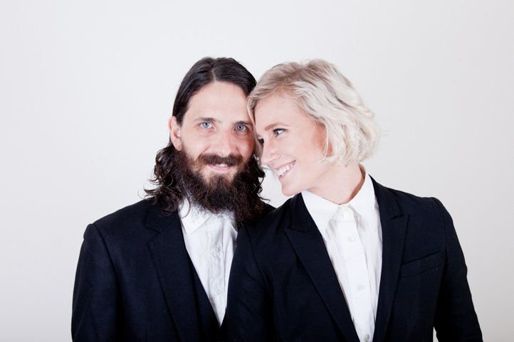 Randy &amp; Kelsey Taylor lean heads on eachother while wearing suits in their home in Hudson, NY