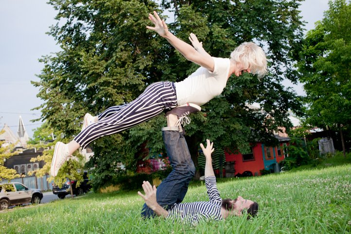 Randy lifts Kelsey Taylor up in the airplane pose with his feet in the grass in the yard of their home in Hudson, NY
