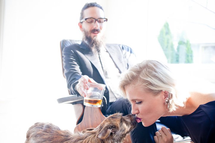 Randy holds a cocktail in an office chair, while Kelsey Taylor kisses the dog in the foreground