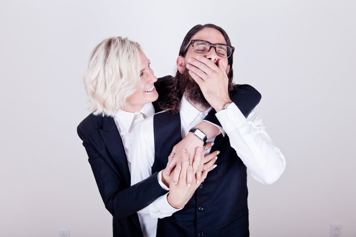 Randy &amp; Kelsey Taylor laugh while wearing suits in their home in Hudson, NY