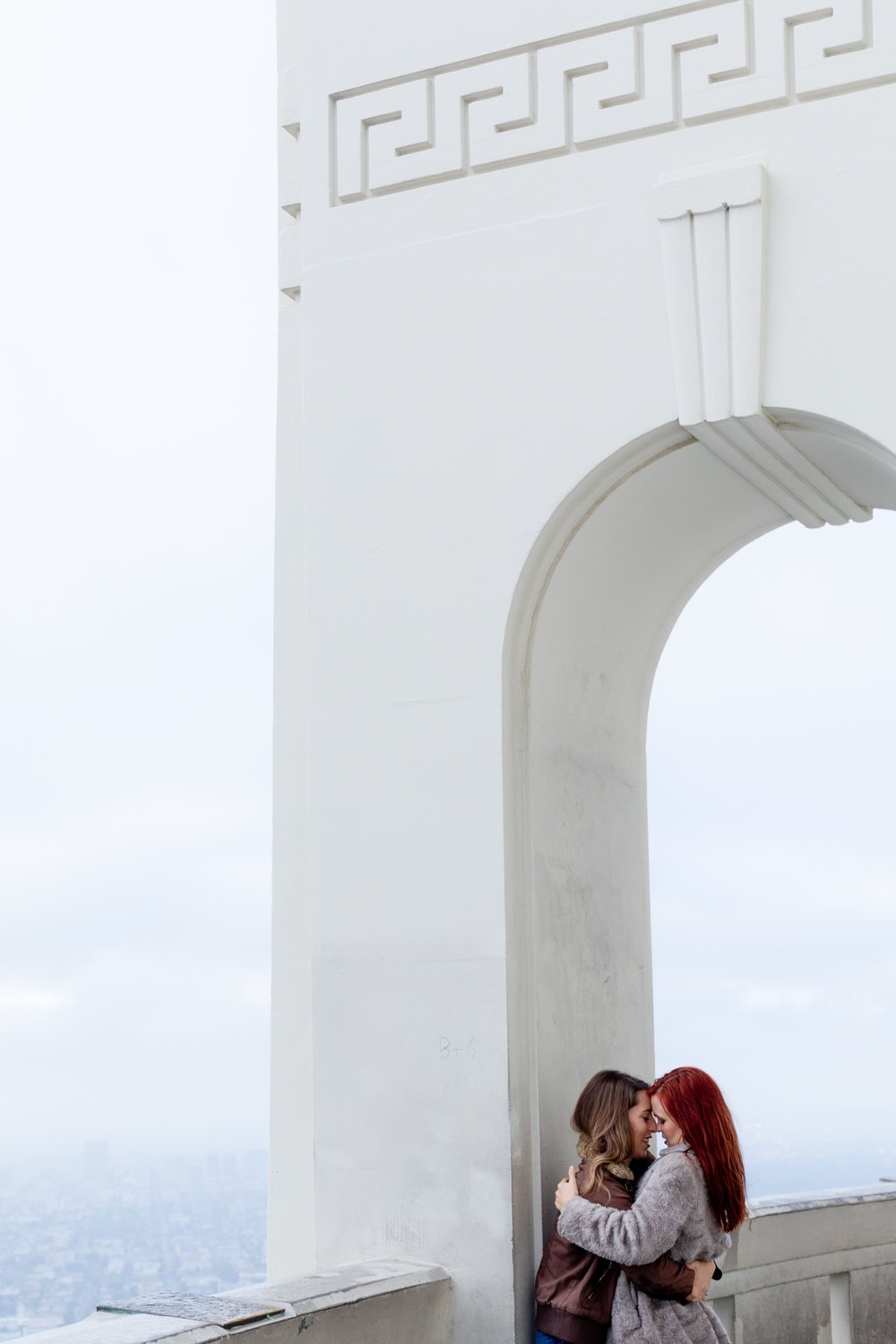 Grace &amp; Tierney kissing under an arch at Griffith observatory in LA