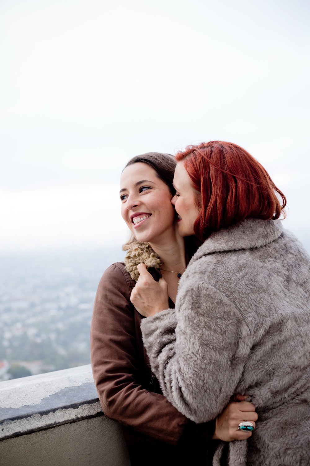 Grace &amp; Tierney kissing, smiling with Los Angeles in the background
