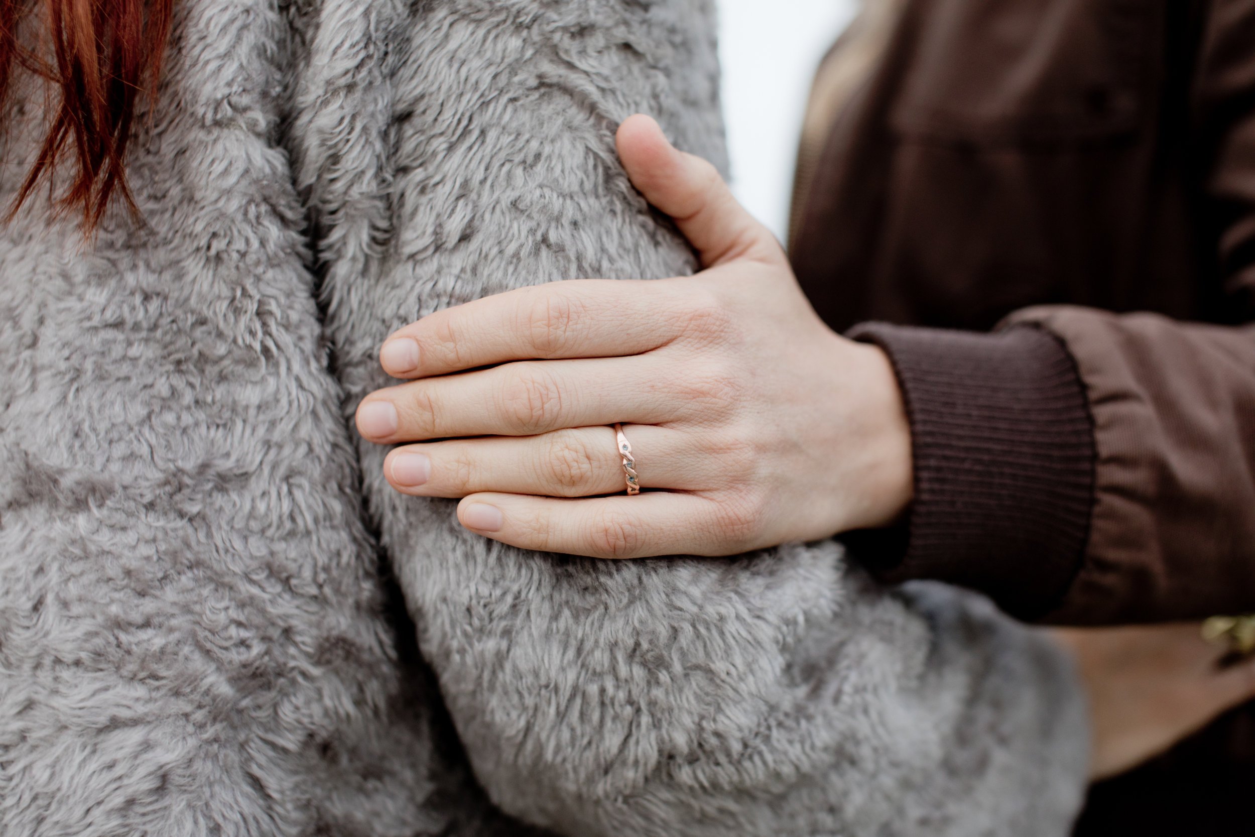 Close up of ring on women's hand, holding onto the arm of her partner