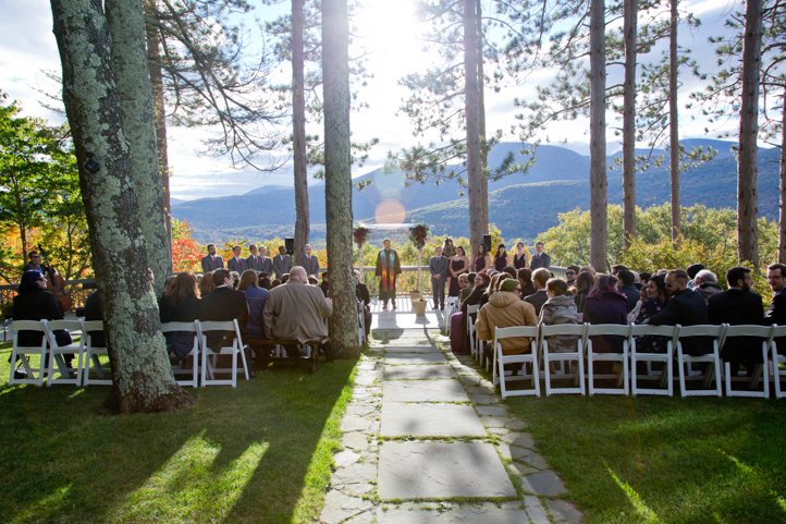 Wide shot of the wedding audience and altar featuring the wedding arch with the autumnal Catskills in the background