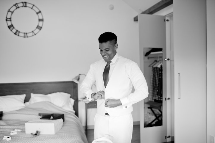 Black and white portrait of Arthur fastening the buttons of his all white tux in a cabin in the Catskills