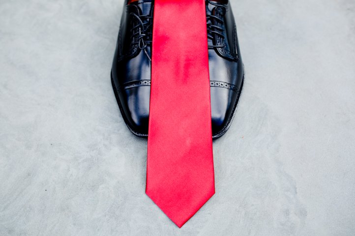 One groom's red tie laying atop his shoes