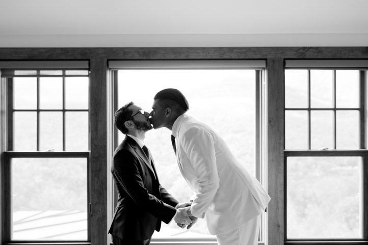 A black and white photo of  Arthur &amp; Scott kissing each other in front of a bright window