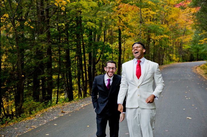 Arthur &amp; Scott laugh on a wooded street surrounded by fall foliage in the Catskills