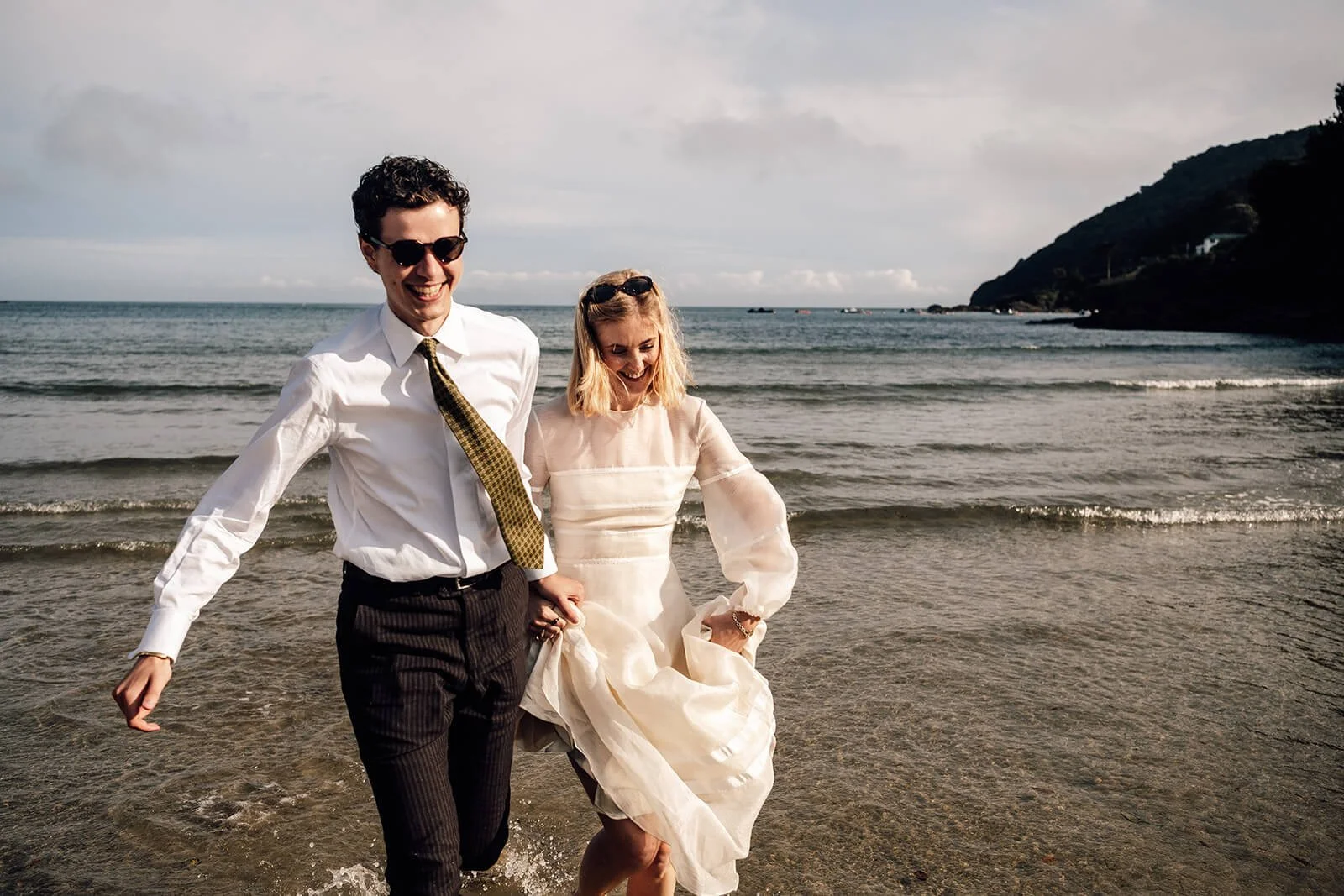 bride and groom running in the sea near Devon