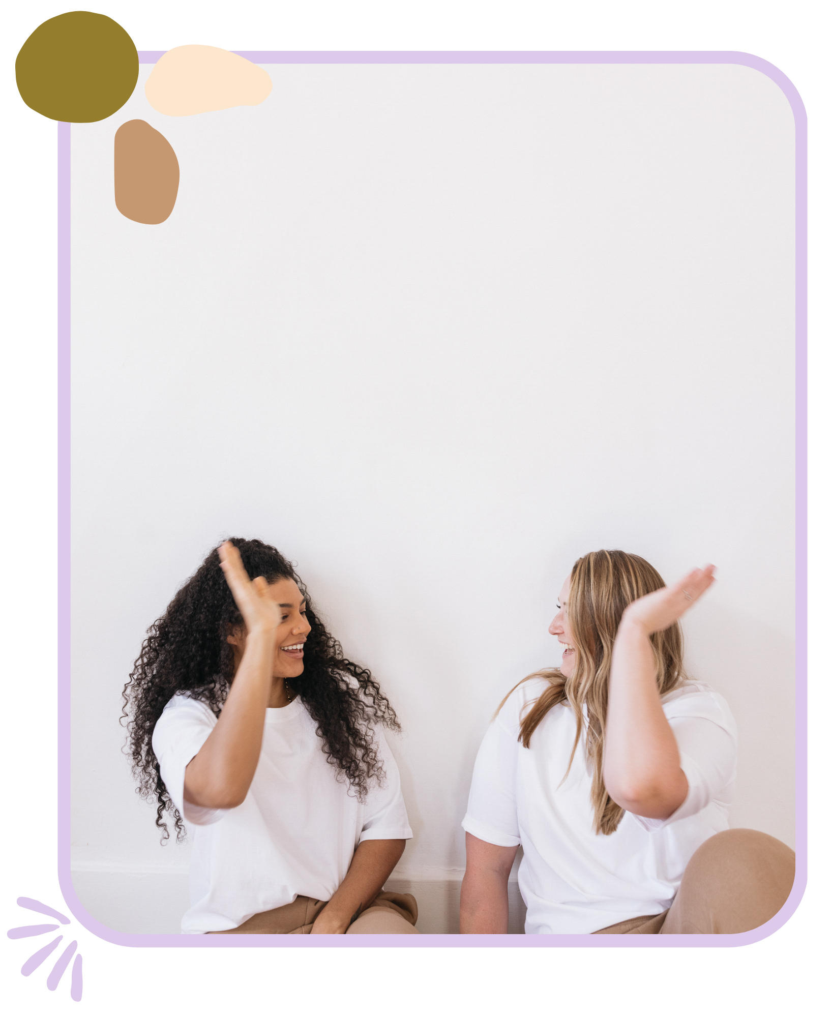 Two young women doing a high-five, while they sit on the floor.