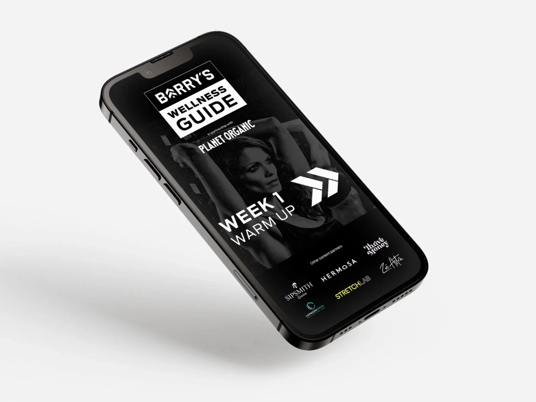 Smartphone displaying a wellness guide app titled 'Barry's Wellness Guide' with a black and white image of a woman, scheduled for week 1 warm-up, with various partner logos at the bottom.