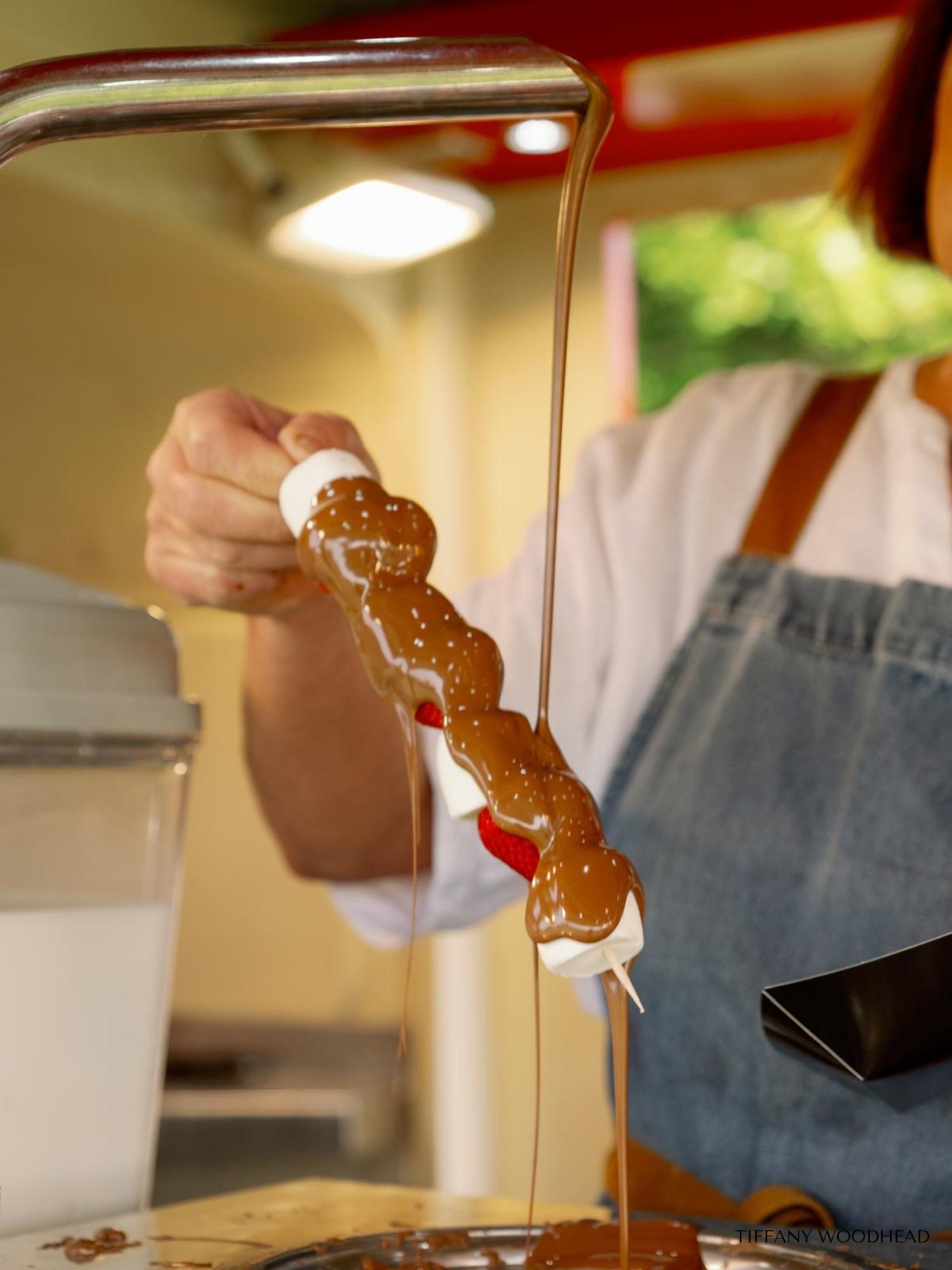 Close-up of a person holding a chocolate and vanilla ice cream popsicle over a plate, with melted chocolate dripping down.