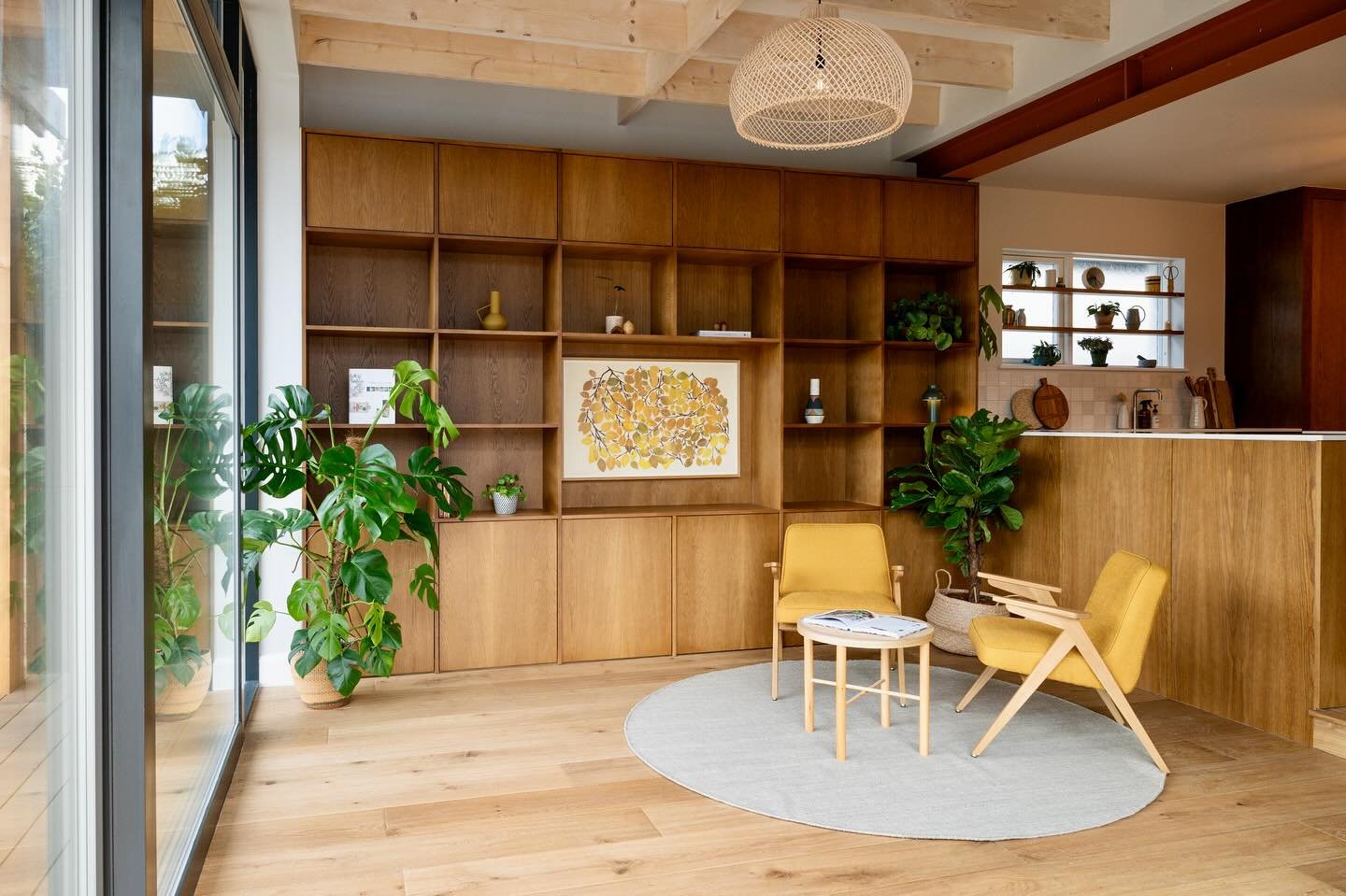 This open-plan living area was designed to feel inviting and comfortable, with a focus on earthy tones and layered textures. A mix of wood and greenery adds warmth and depth, while statement furniture, accessories, and artwork bring the whole space t