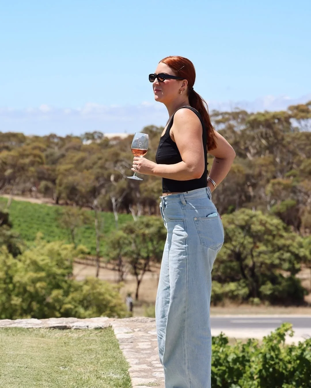 Woman holding a glass of rosé and gazing over the vineyard — capturing the beauty and stillness of Cape Jaffa Wines' rural wine country views.