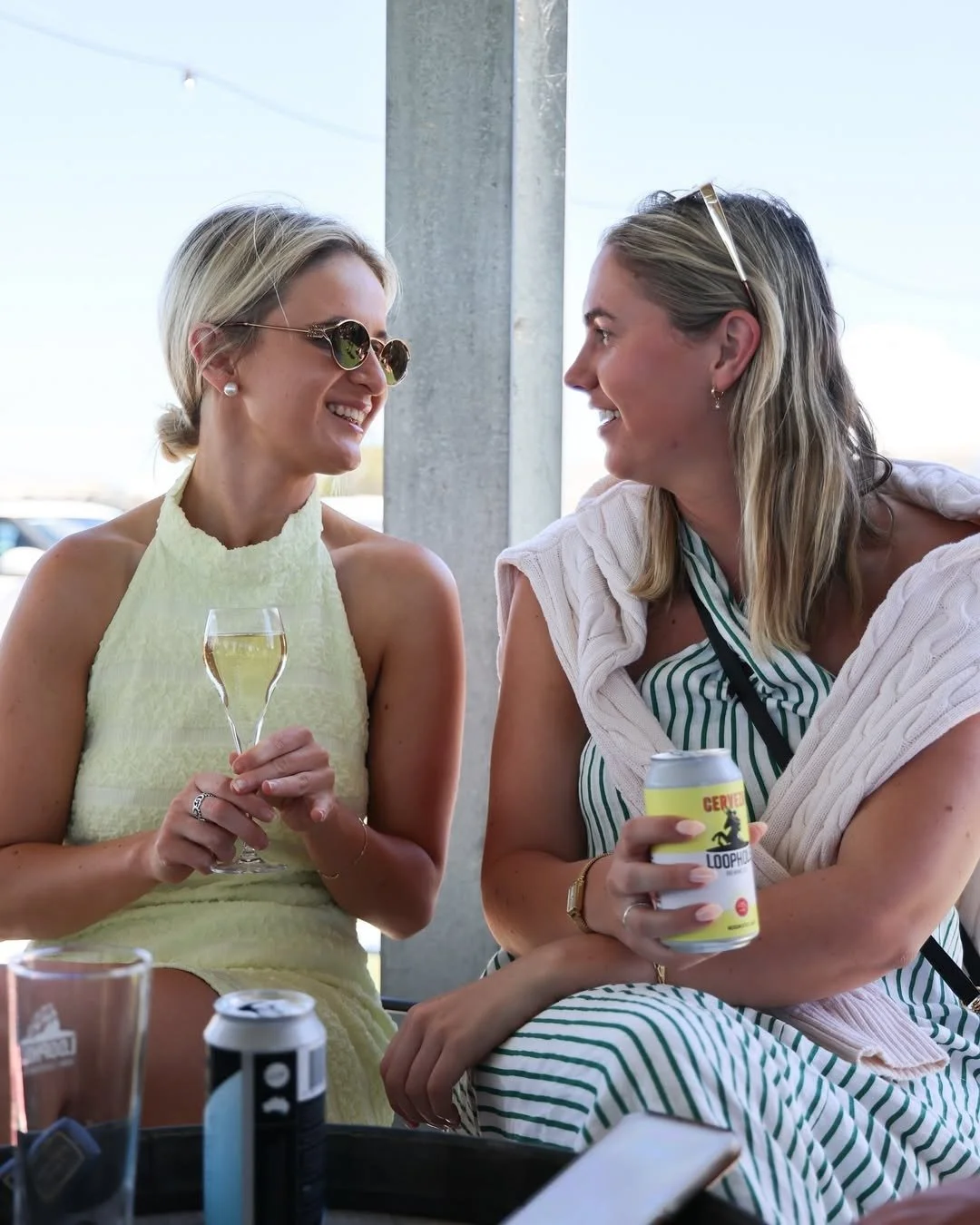 Couple smiling with champagne glasses at Cape Jaffa Wines' vineyard deck — a serene setting for summer escapes and weekend stays on the Limestone Coast.