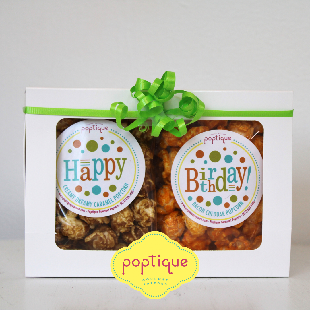 A gift box with a green ribbon and bow containing two bags of popcorn, one labeled "Happy" and flavored like caramel, and the other labeled "Birthday" with bacon cheddar flavor, from Poptique Gourmet Popcorn.