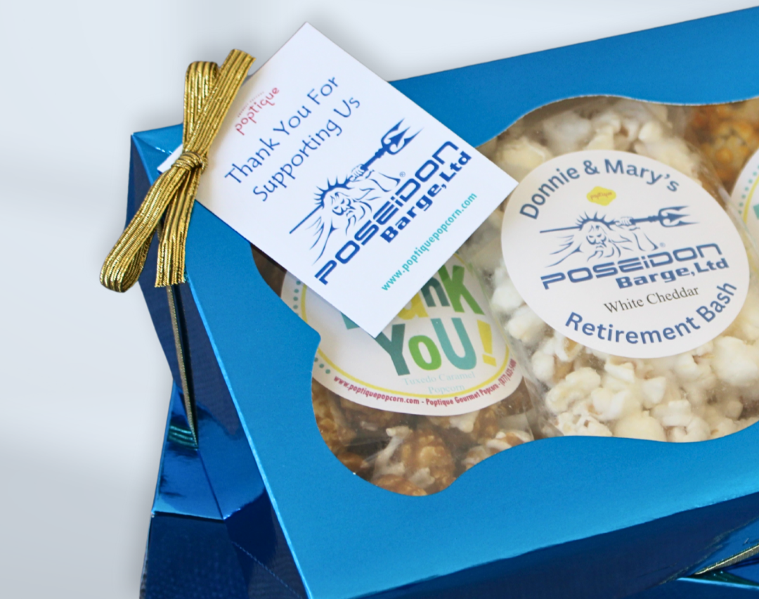 A blue gift box with a gold ribbon, containing popcorn snacks with acknowledgments for support from Poseidon Barge Ltd, and labeled as a retirement bash.
