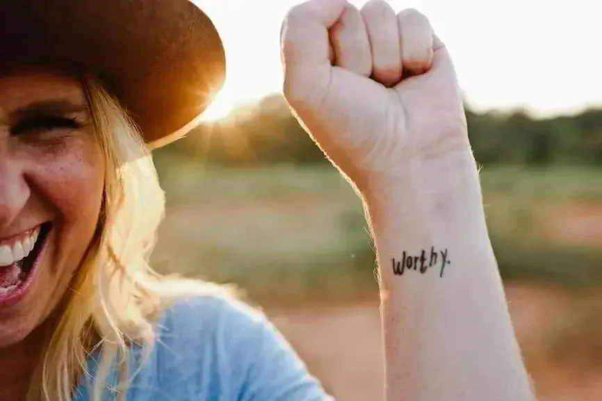 Woman smiling with tattoo of worthy. This image represents the identity and self-worth therapy that Jessika Fruchter LMFT specializes in. Her practice is in Oakland California.