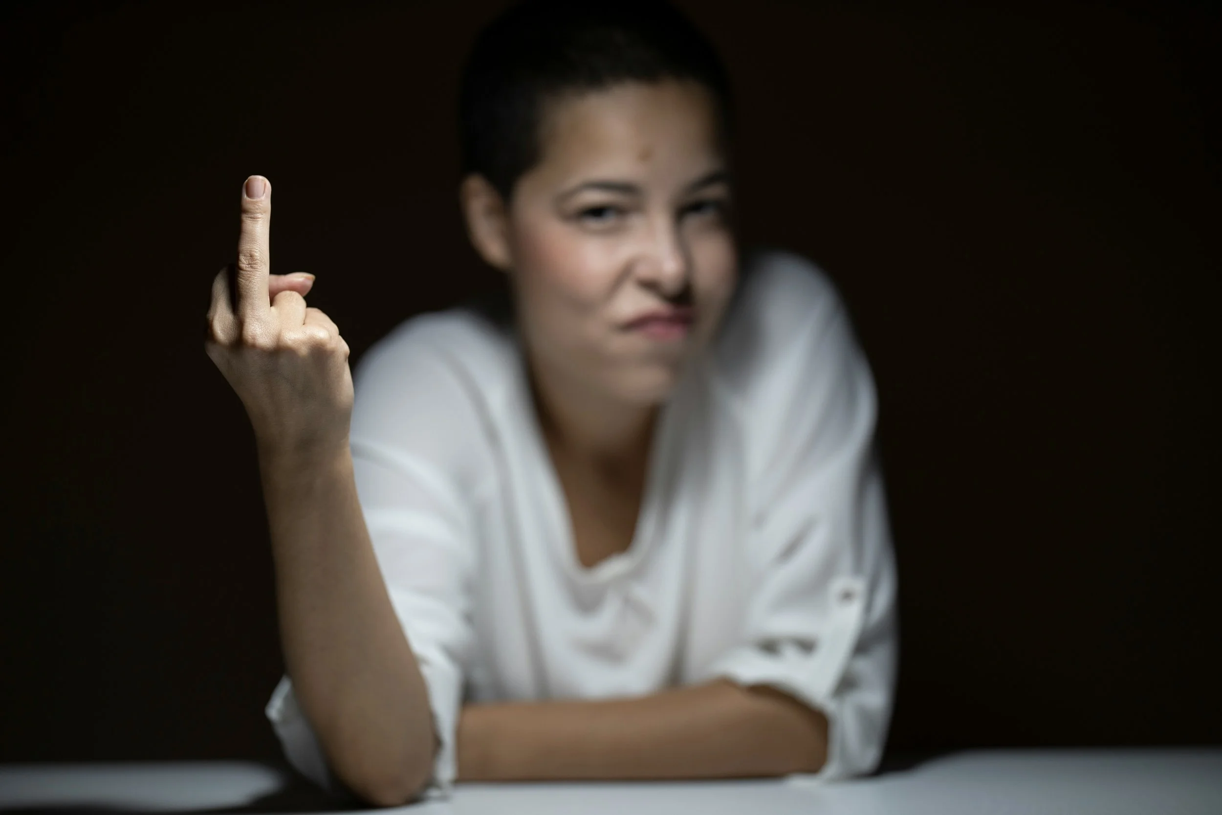 Woman is sticking her middle finger up while glaring at the camera. Image speaks to anger and frustration perimenopausal women experience.