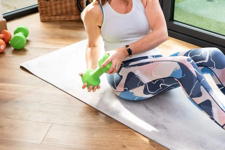 Pilates instructor Alison Marcuse-Harris demonstrating strength training seated with light weights