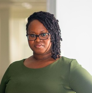 A woman with glasses and black hair, wearing a green shirt