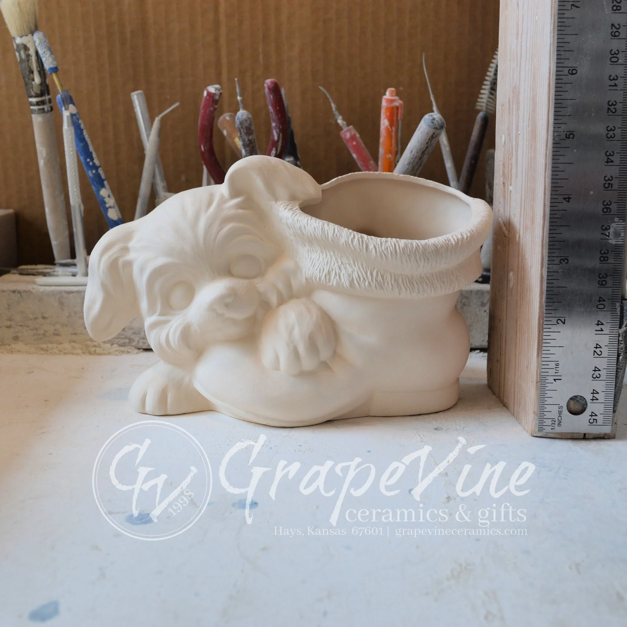 Unpainted ceramic puppy with Santa boot – Duncan DM‑1918 mold, front view with ruler for scale