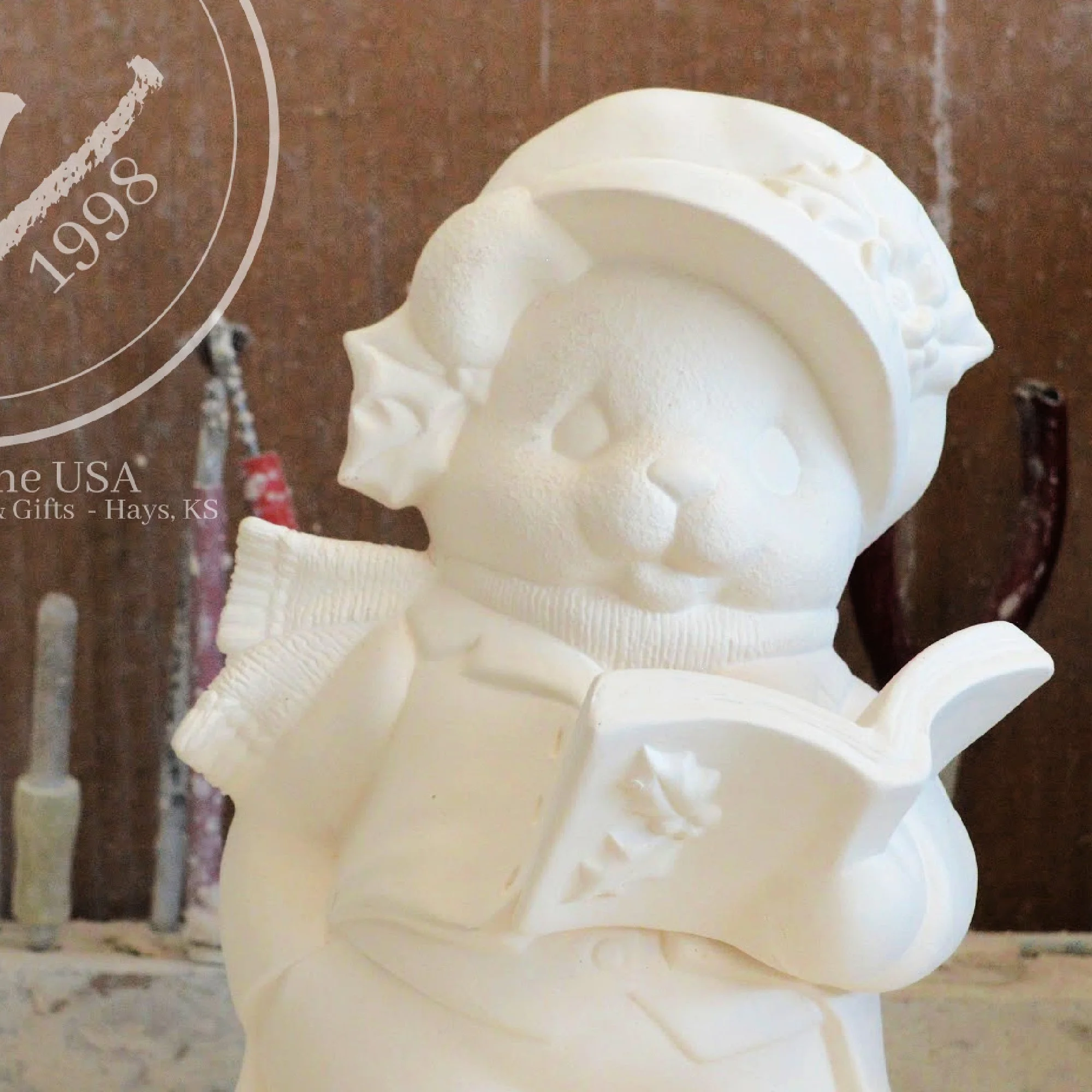 Close-up of poinsettia floral details and texture on the ceramic Christmas bear’s hat and coat.