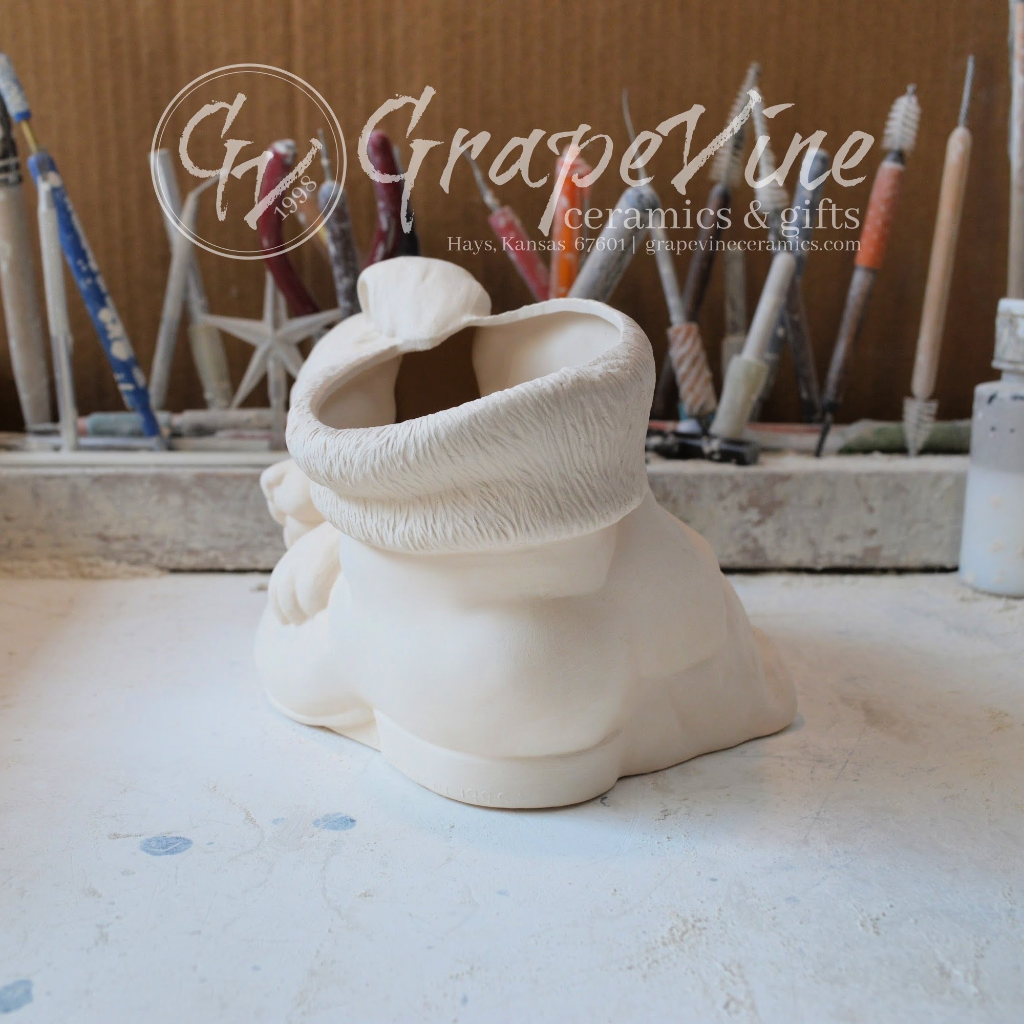 Side angle of ceramic bisque puppy leaning on Santa boot, ready to paint