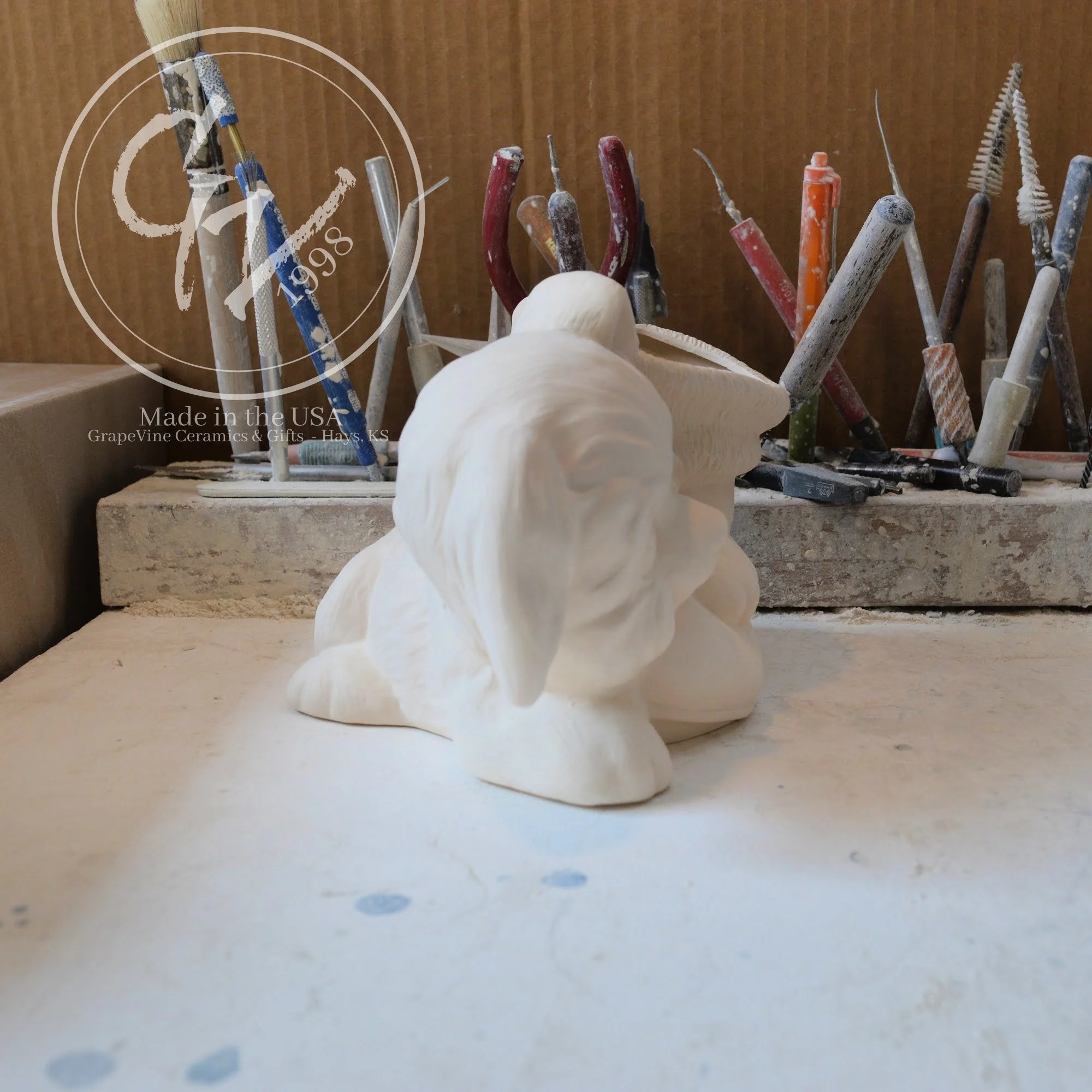 Side angle of ceramic bisque puppy leaning on Santa boot, ready to paint