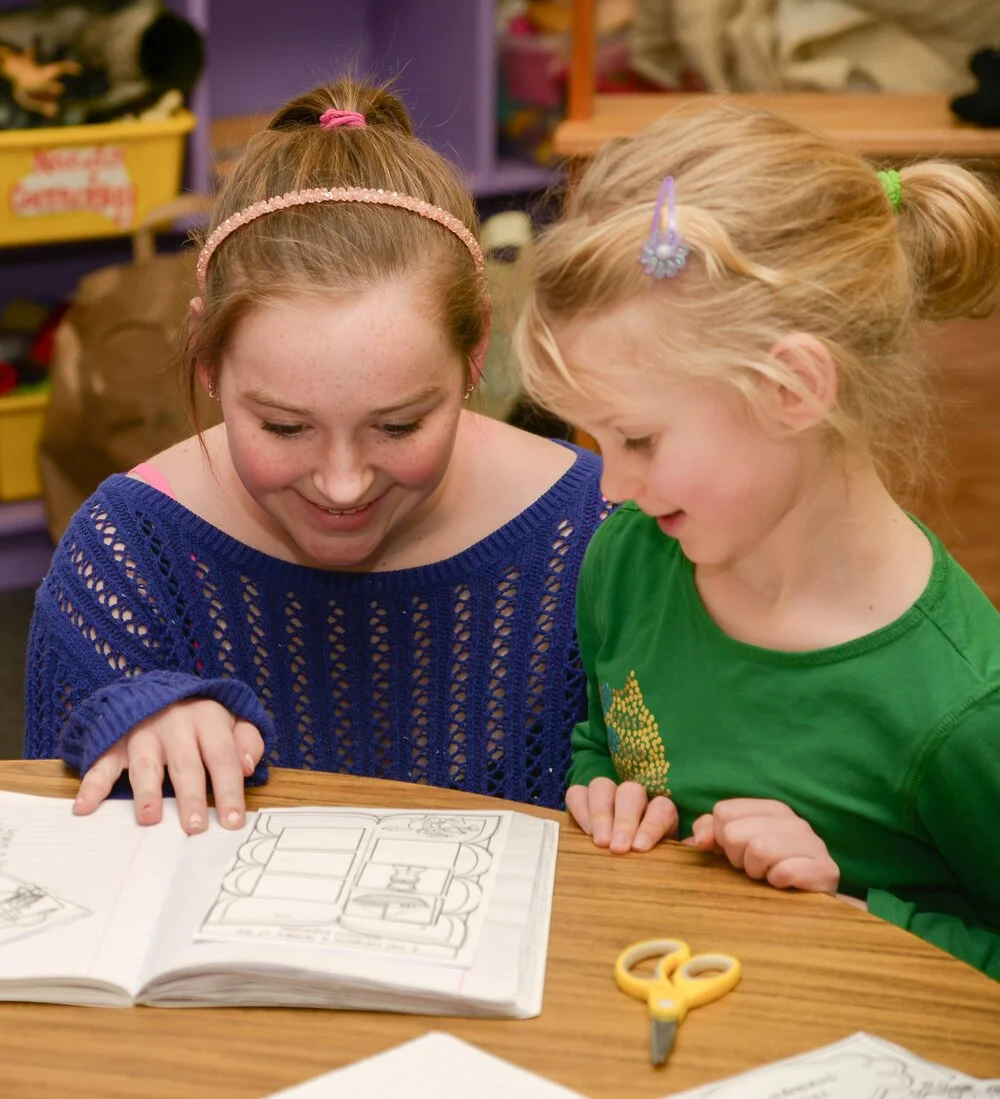 Clark School teacher and kindergartener looking at a craft book