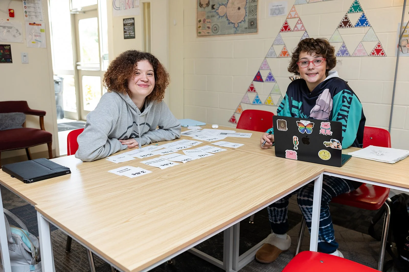Two Clark School high school students doing a math activity, looking at camera smiling