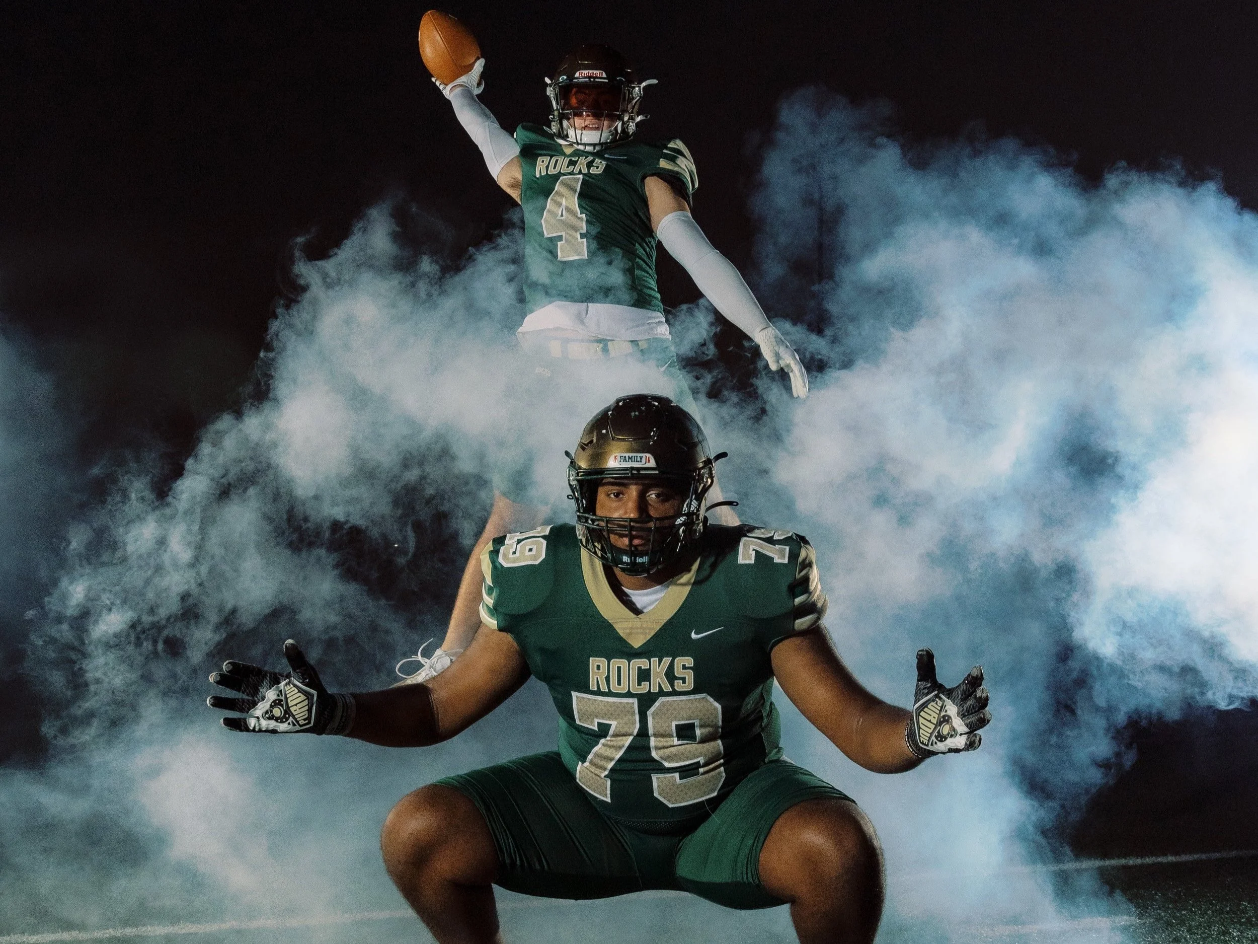 an outdoor media sports session with two senior football players on the high school football field with dramatic lighting and fog effects