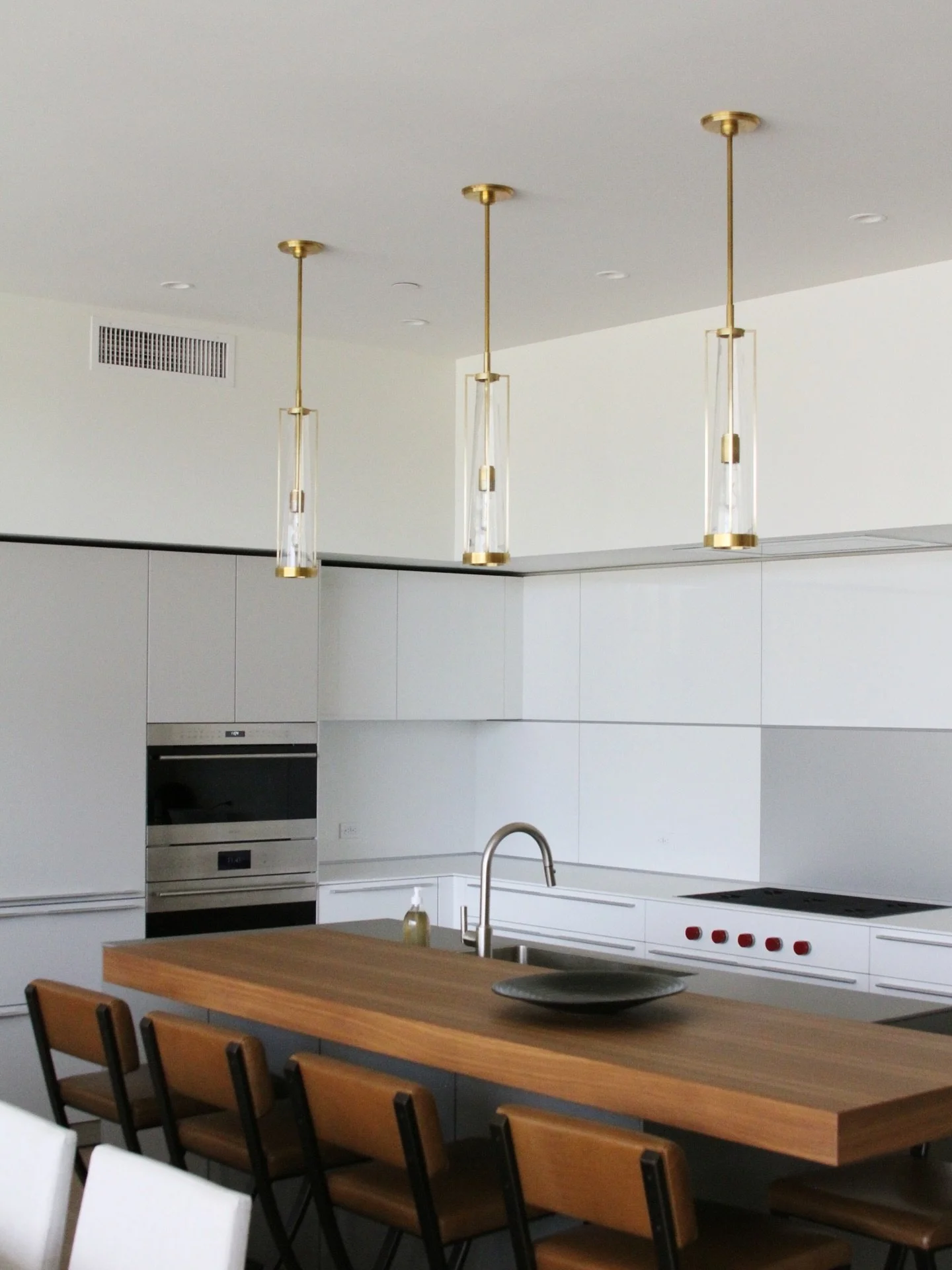 A sleek island creates the perfect spot to enjoy a cup of coffee or have a casual meal. Gorgeous glass and gold pendants allow light to seep through and add a touch of warmth to this neutral and grounding space. ✨️#LygiaHarkinsInteriors ⁠
⁠
⁠
⁠⁠#inte