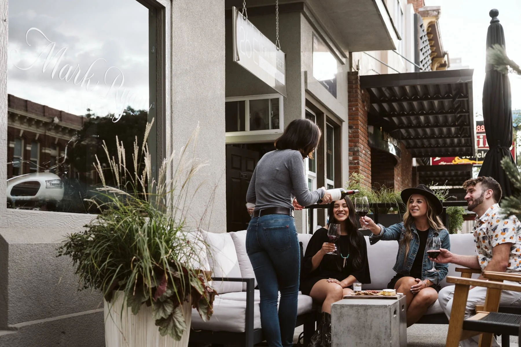 The patio at the Mark Ryan Winery Walla Walla tasting room, with three friends being poured wine by a team member.