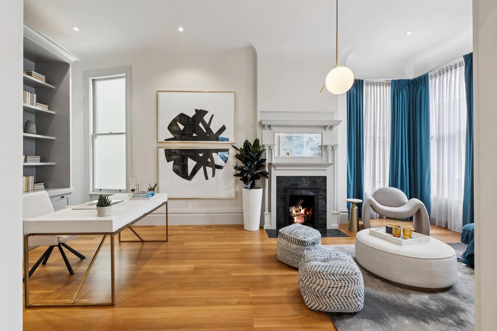 Living room with a fireplace, blue curtains, a table, a chair, and decorative items.