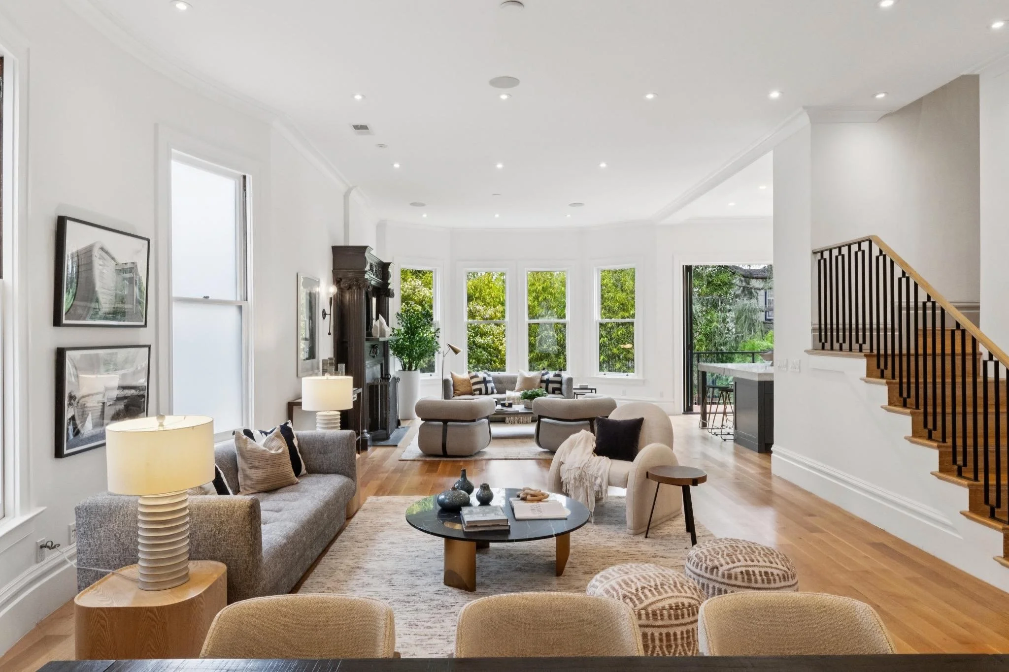 Living room with large windows, beige and gray furniture, wooden floors, and decorative items.