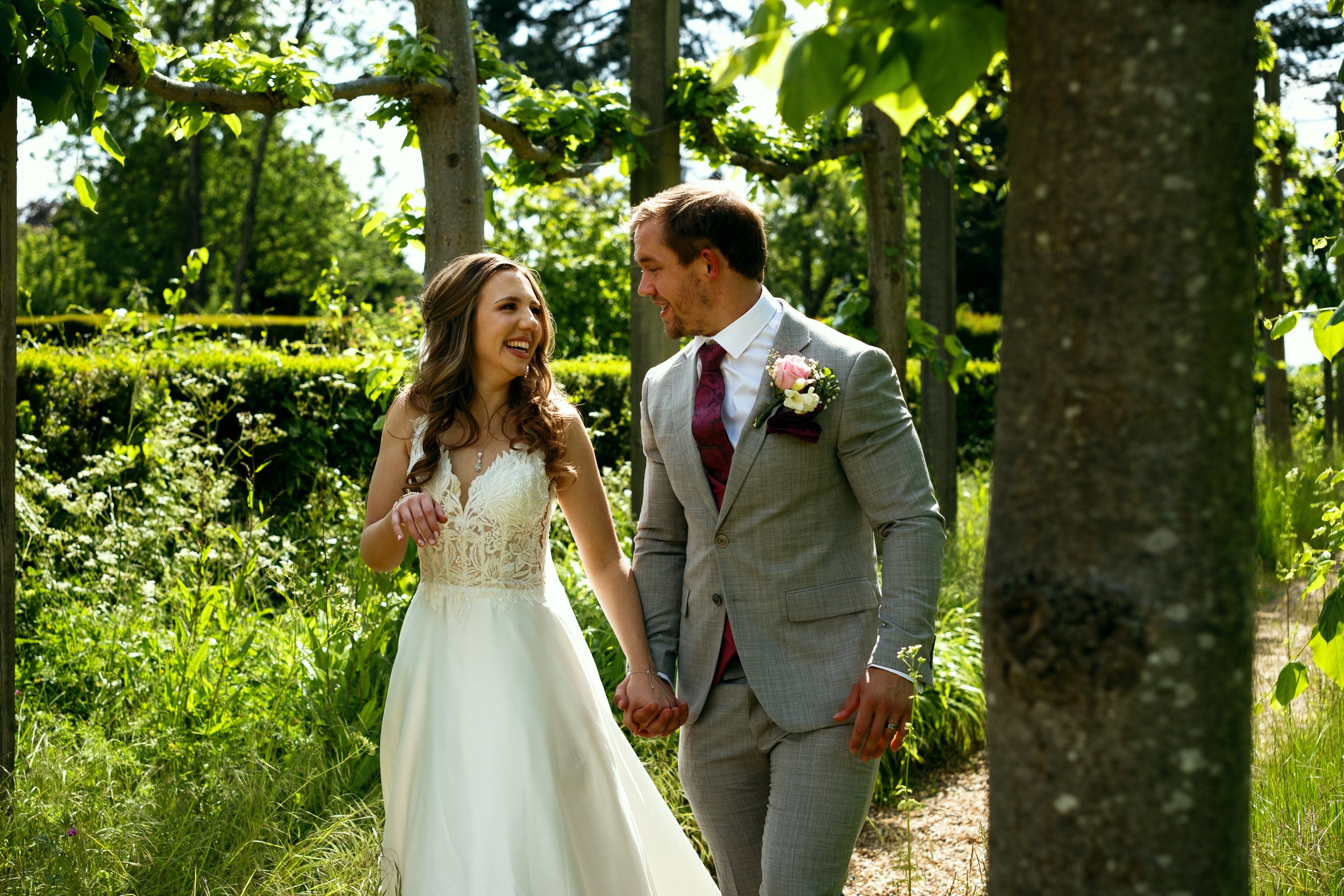 a young wedding couple take a walk in the gardens of fanhams hall in hertfordshire