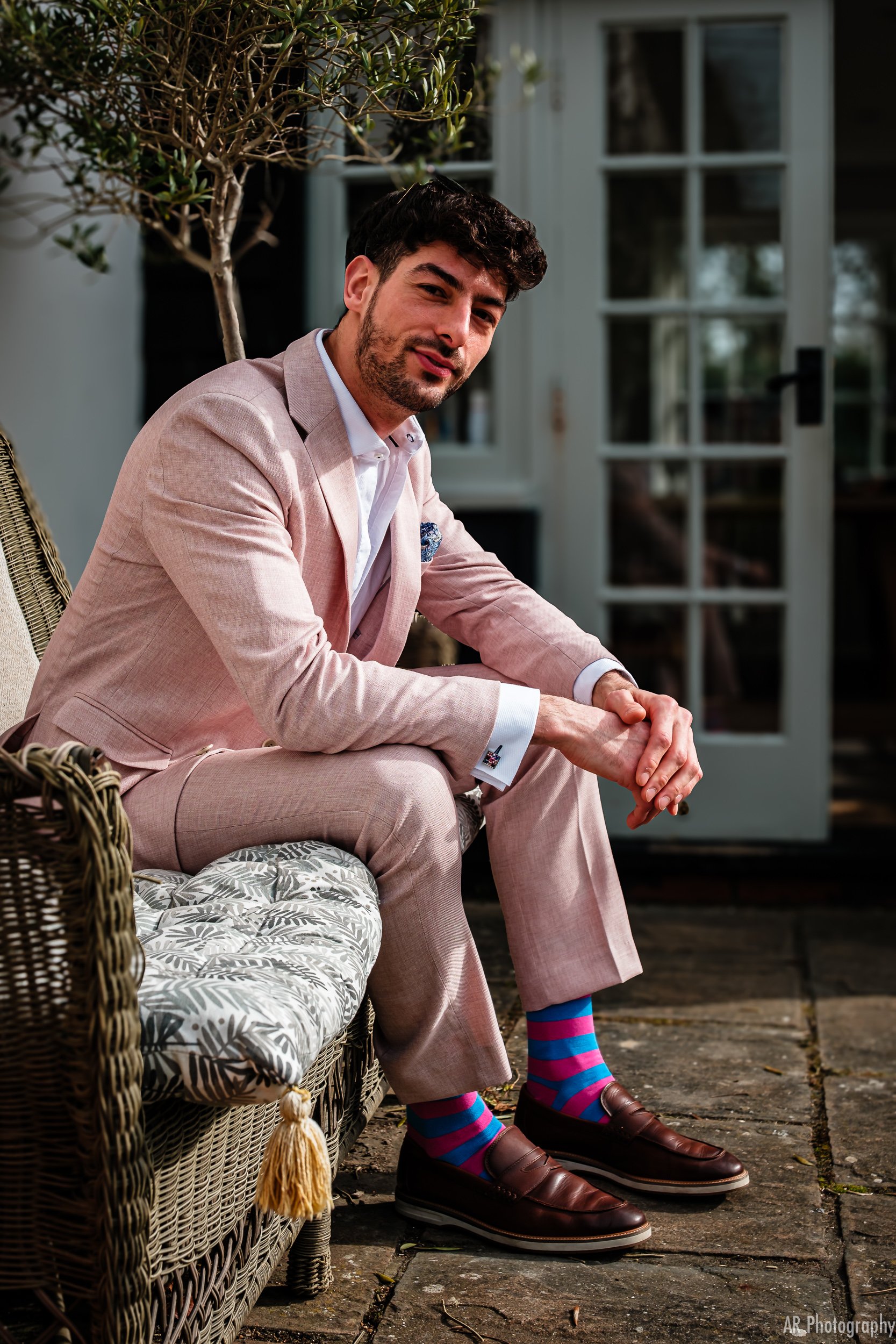 a model in a pink pastel linen suit posing outside in a garden in cambridge