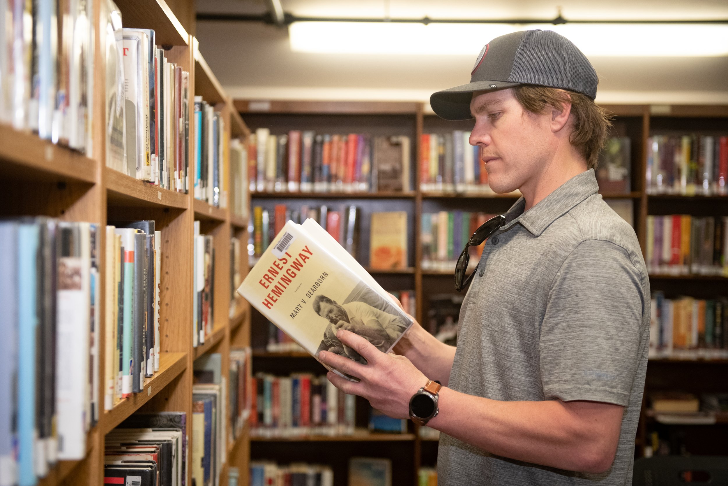 man with baseball hat reading book standing