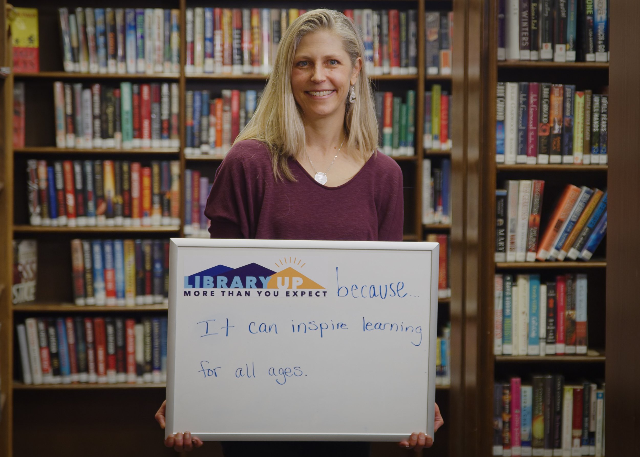 woman holding whiteboard about why she loves the library