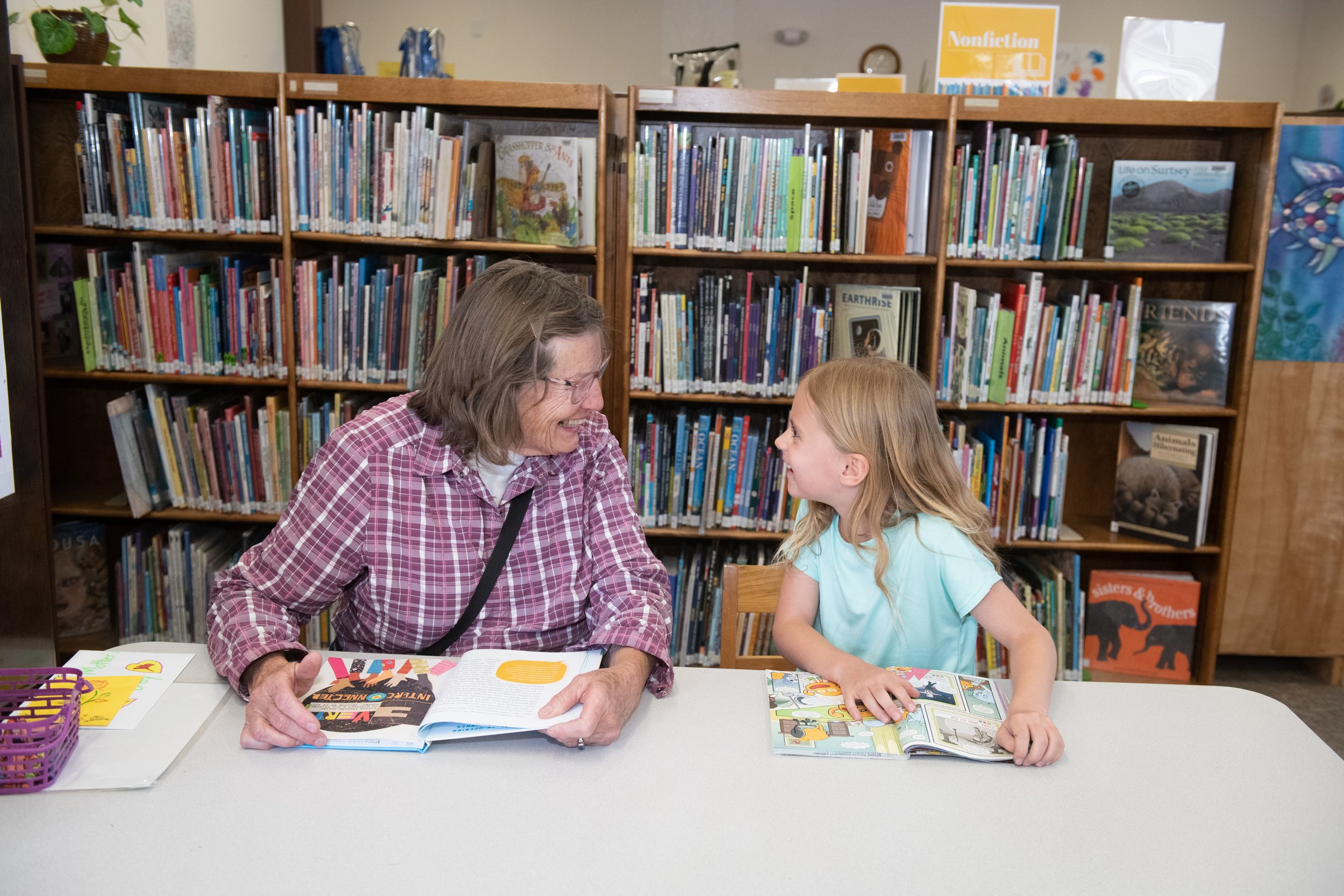 older woman and little girl smiling at each other at library